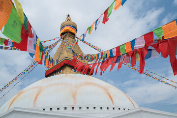 Multicolored praying flags with Mantras texts hinged on the top of Boudhanath Stupa-the largest spherical stupas in Nepal and very sacred place for Buddhists. Traveling around the world concept image.