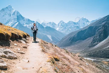 Foto op Plexiglas Ama Dablam Young hiker backpacker female taking a walking with trekking poles during high altitude Everest Base Camp route near Dingboche,Nepal. Ama Dablam 6812m on background. Active vacations concept