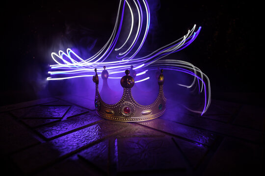 low key image of beautiful kings crown over wooden table. vintage filtered. fantasy medieval period. Selective focus.