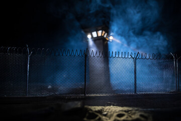 Old prison watchtower protected by wire of prison fence at night. Creative art decoration....