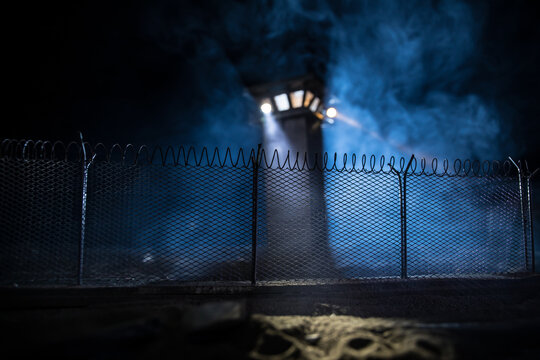 Old prison watchtower protected by wire of prison fence at night. Creative art decoration. Selective focus