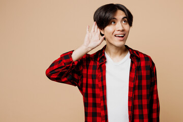 Young curious nosy man of Asian ethnicity wear red checkered shirt casual clothes try to hear you...
