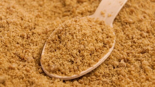 Unprocessed unrefined brown raw sugar in bamboo teaspoon. Natural sweetener. Rotation