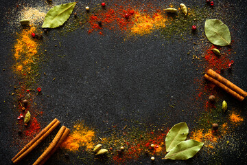 Spices and herbs on black slate background. Pepper, turmelic, dill, cinnamon, basil, rosemary,...