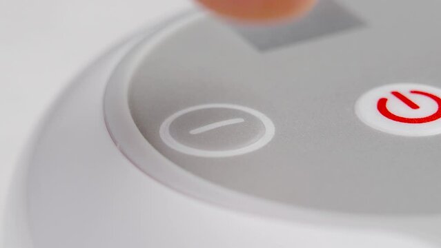 Pressing the Minus button of an electronic device to reduce the supply of electrical power. Macro shot