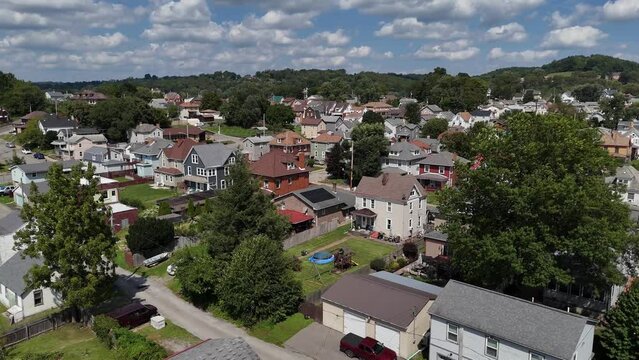 A rising aerial summertime establishing shot view of a typical rust belt Pennsylvania middle-class residential neighborhood. Pittsburgh suburbs.  	