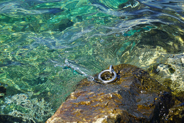 Hook on the stone immersing in the transparent sea water