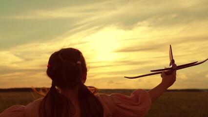 Happy girl child runs with toy plane sunset. Girl kid playing aviator. Kid dream of becoming an...