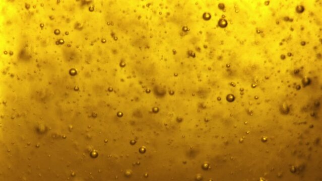 Small bubbles in the yellow liquid slowly rise to the top. beer or gel, shampoo or oil