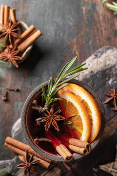Mulled wine in ceramic mug with orange slices and spices top view. Christmas hot drink on wooden table with xmas tree branches, festive card