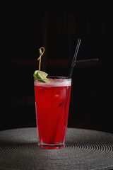 Red Campari cocktail with lime in a glass tumbler and drinking tube, bar cocktail in a restaurant