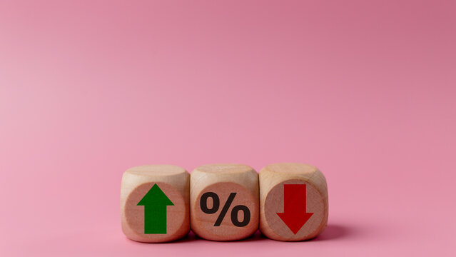 Wooden cubes with green arrow and red arrow with icon percentage symbol on pink background. Interest rate financial and mortgage rates concept.