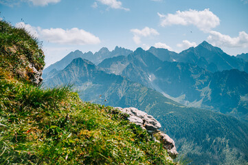 Fototapeta na wymiar High Tatras from the Belianske Tatras, where emerald meadows meet the towering peaks, all beneath a sky of boundless blue