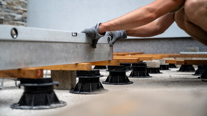 Man in protective gloves leveling aooden supporting construction for a terrace