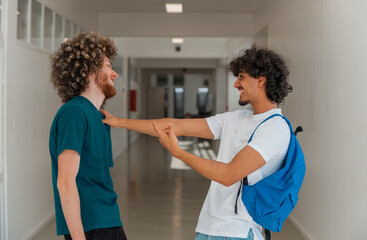 Obraz premium Two happy male college students having fun while talking with each other on a university campus.