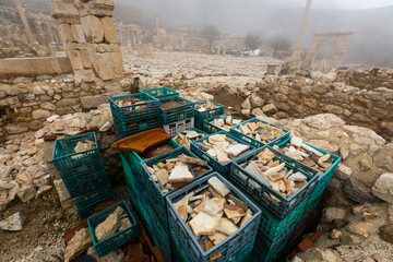 Boxes with stones and architectural elements on ruins of ancient Pisidian town of Sagalassos on foggy winter day, Turkey