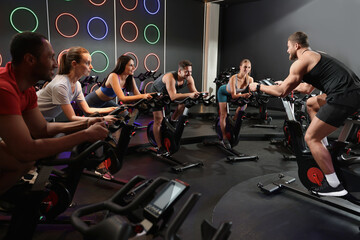 Group of people training on exercise bikes in fitness club - Powered by Adobe