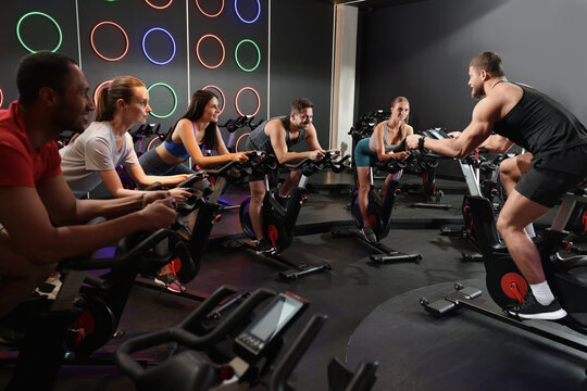Group of people training on exercise bikes in fitness club