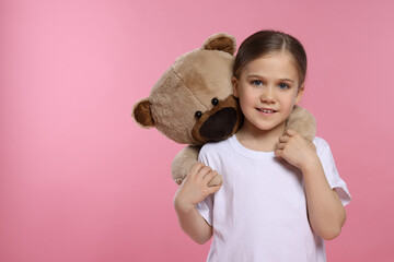 Cute girl with teddy bear on pink background, space for text