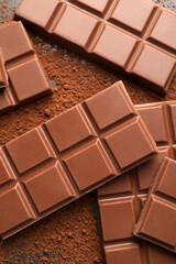 Delicious milk chocolate and cocoa powder on grey table, flat lay