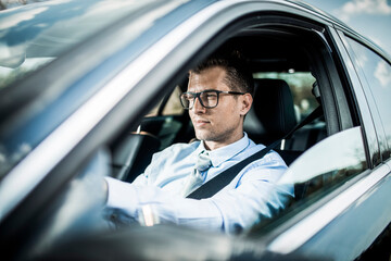 Young caucasian businessman driving a car to work