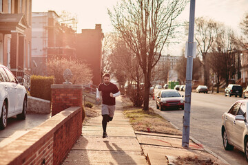 Young man jogging on a sidewalk in the suburb