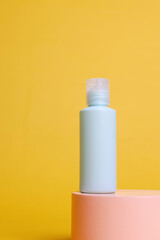 Green sage mockup bottle of body cream on a pink podium isolated on yellow background.