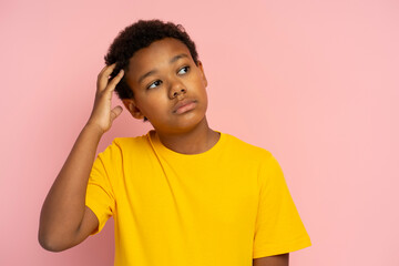 Portrait of serious pensive Nigerian boy wearing stylish yellow t-shirt thinking looking away © Maria Vitkovska
