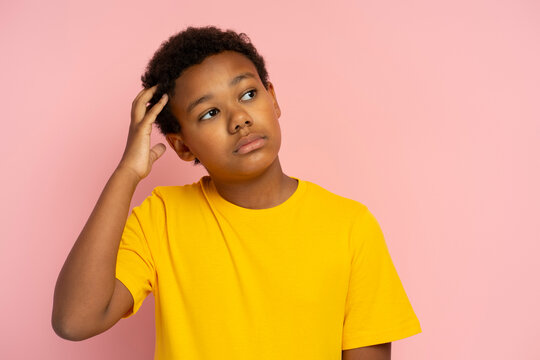 Portrait of serious pensive Nigerian boy wearing stylish yellow t-shirt thinking looking away