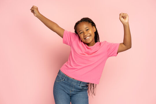 Positive African girl with stylish dreadlocks wearing casual clothes with hands up, having fun