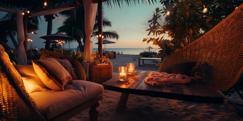 Poster cozy Luxury resort, evening beach, candles blurred light on table ,sofa, hammock on front sunset sea ,tropical plan and palm © Aleksandr