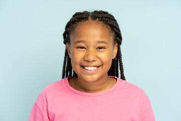 Portrait of cute smiling African American girl wearing stylish hairstyle, dreadlocks isolated on blue background