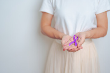 Woman holding purple Ribbon for Violence, Pancreatic, Esophageal, Testicular cancer, Alzheimer, epilepsy, lupus, Sarcoidosis and Fibromyalgia. Awareness month and World cancer day concept