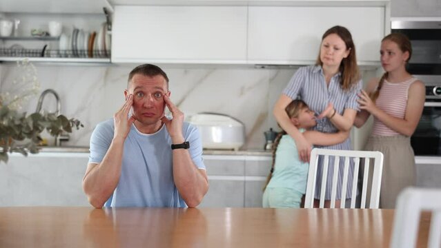 Irritated dissatisfied woman yelling at confused husband in home kitchen. Two frustrated teenage girls sitting at table during parental quarrel, selective focus. High quality 4k footage