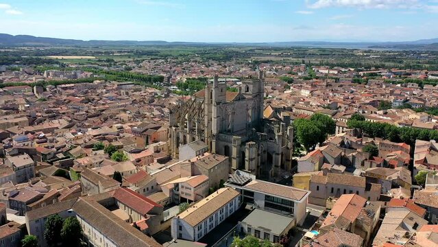 Drone shot, drone video, drone flight, aerial view, flight over the historic old town with central view of the cathedral of Narbonne (French Cathedrale Saint-Just-et-Saint-Pasteur de Narbonne), blue