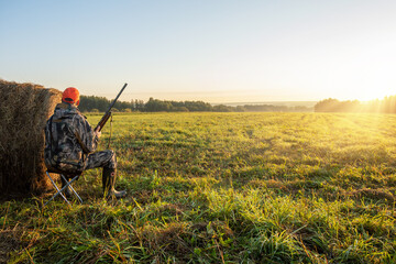 hunter with a gun in the field at dawn. Hunter in the nature. Hunting season.