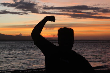 Silhouette of a young man standing by the lake enjoying the sunset. peaceful atmosphere in nature
