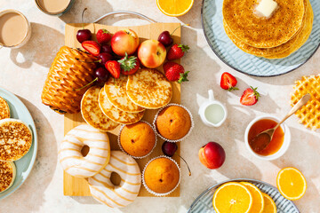 Sunny summer breakfast with a variety of pastries, fruits, berries and coffee with milk. Top view.