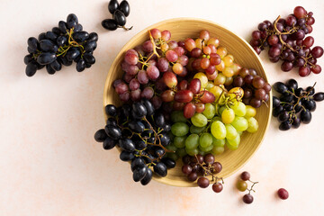 Black, red and green grapes in a bowl. Top view, flat lay.