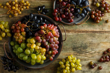 Diverse assortment of grapes on a wooden background. Autumn harvest. Top view. Selective focus.