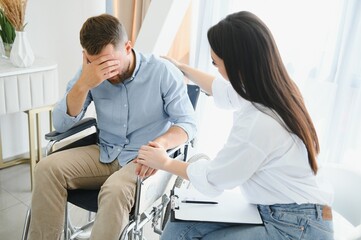 Young disabled man talking to female psychologist at home