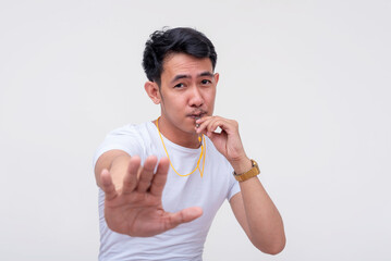 A serious asian guy blowing his whistle telling you to stop. Isolated on a white background.
