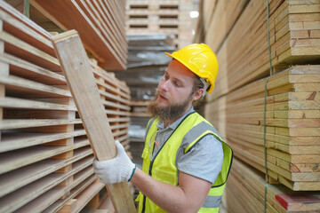 Warehouse worker working at lumber yard in Large Warehouse. Worker are  Inventory check at Storage shelves in lumberyard.