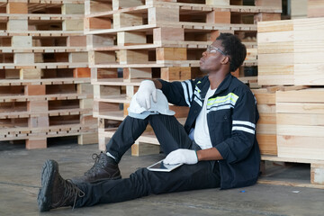 African American worker examining stock of timber while working at wood warehouse.