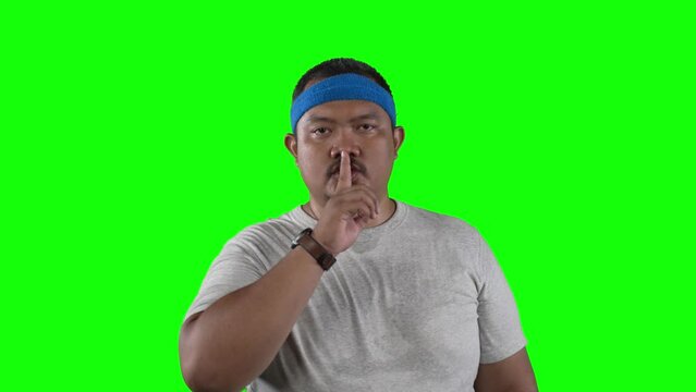 Overweight Asian man puts his finger to his lips