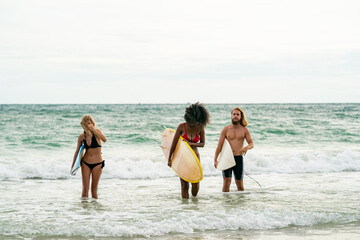 Happy friends with surfboards on the beach