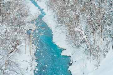 Shirahige Waterfall with Snow in winter, Biei river flow into Blue Pond. landmark and popular for attractions in Hokkaido, Japan. Travel and Vacation concept - obrazy, fototapety, plakaty