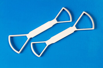 Two universal scrapers for cleaning the tongue on a blue background. Personal hygiene products....