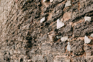 An old medieval stone wall, grass and moss on it. Wallpaper, natural background, copy space, soft focus.