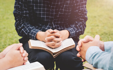 Christian life bible study concept Group of Christian friends sitting together studying the Bible Outdoors in the park and pray together and live according to God's word